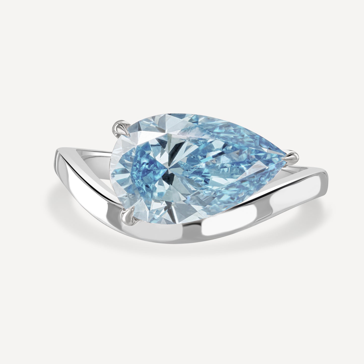 Close up of 3 carat blue pear-cut lab-grown diamond Drift Float Ring against white background